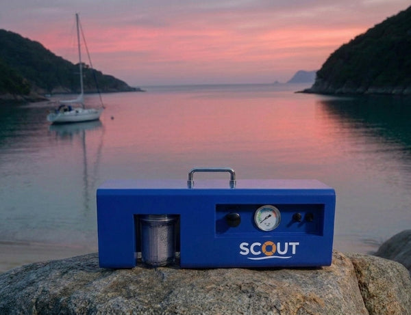 DIY watermaker for boat: LEDI Scout portable reverse osmosis system on Queensland rocks with sailboat at anchor