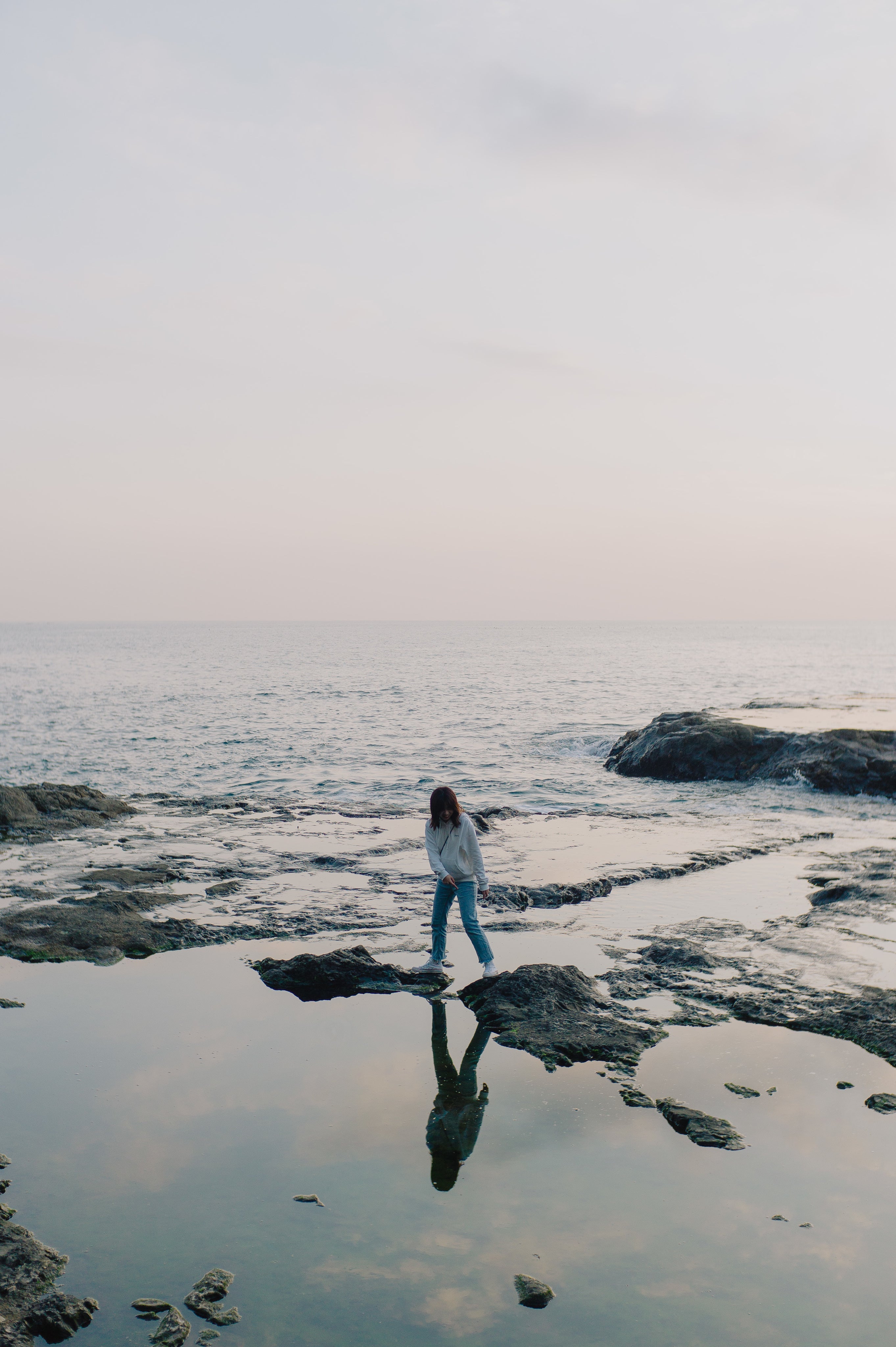 Person standing on rocks at the ocean shoreline