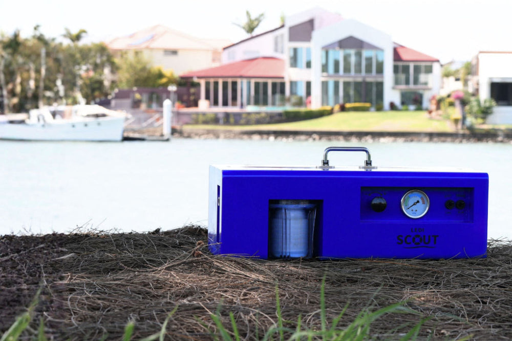 Blue portable air compressor on grass with a waterfront background