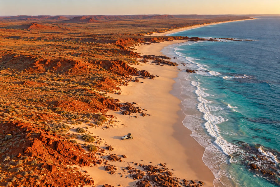 4WD with rooftop tent camped on a remote outback beach beside red cliffs and turquoise water
